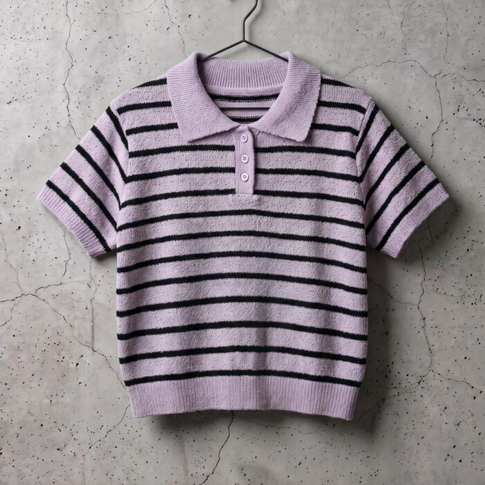 Fioletowa koszulka polo frotte w czarne paski na wieszaku na betonowej ścianie